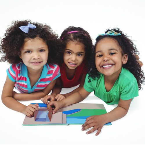 Three girls with a small book against a white background